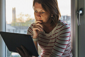 Woman using digital tablet on window sill